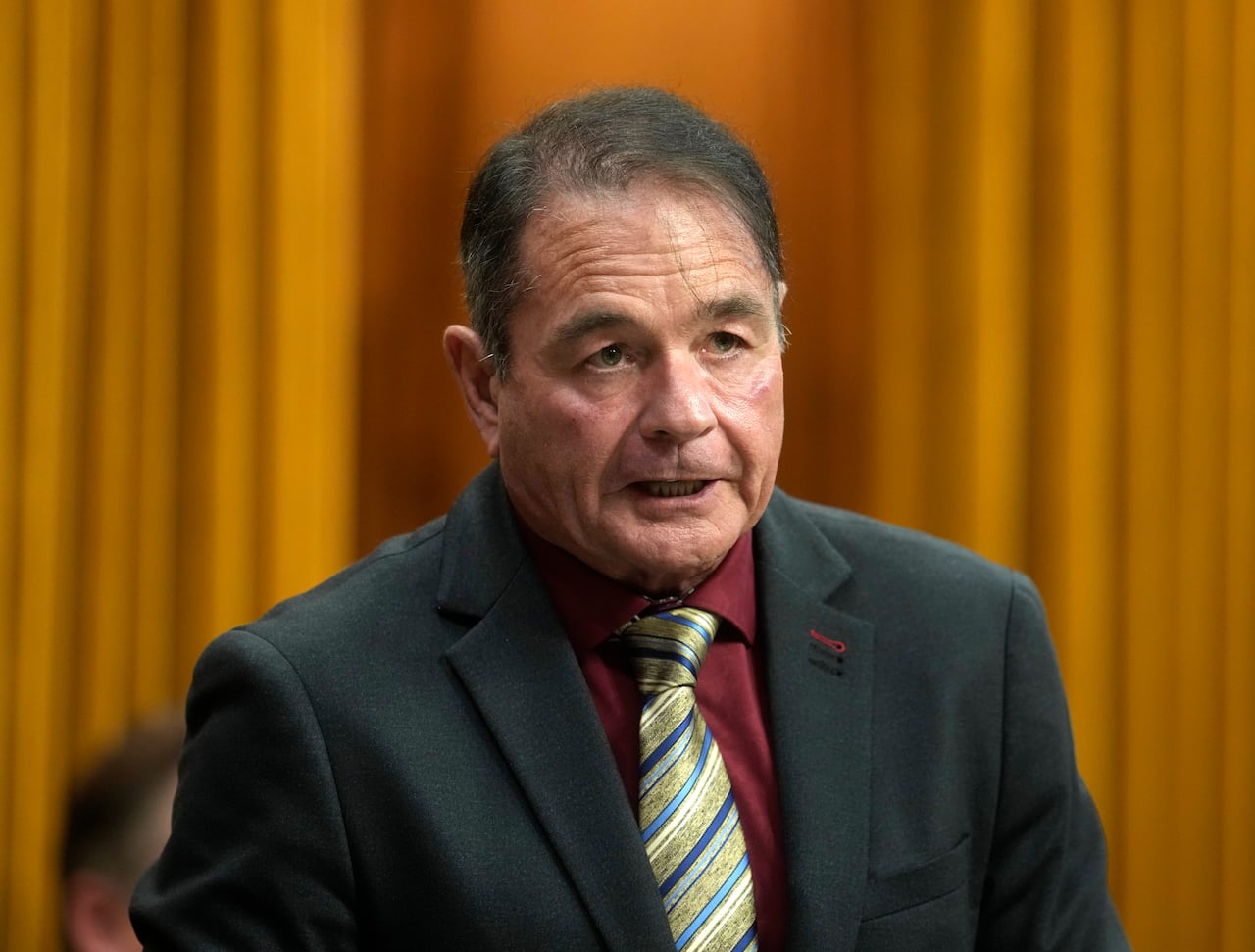 A man wearing a mauve shirt and a patterned gold tie speaks.