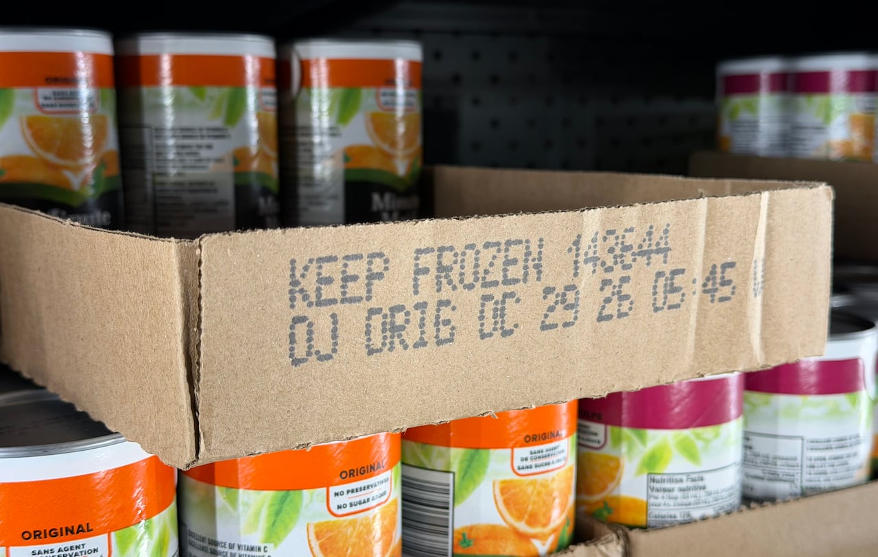 A cardboard palette, printed with the words "Keep Frozen," is partly filled with frozen juice cans.
