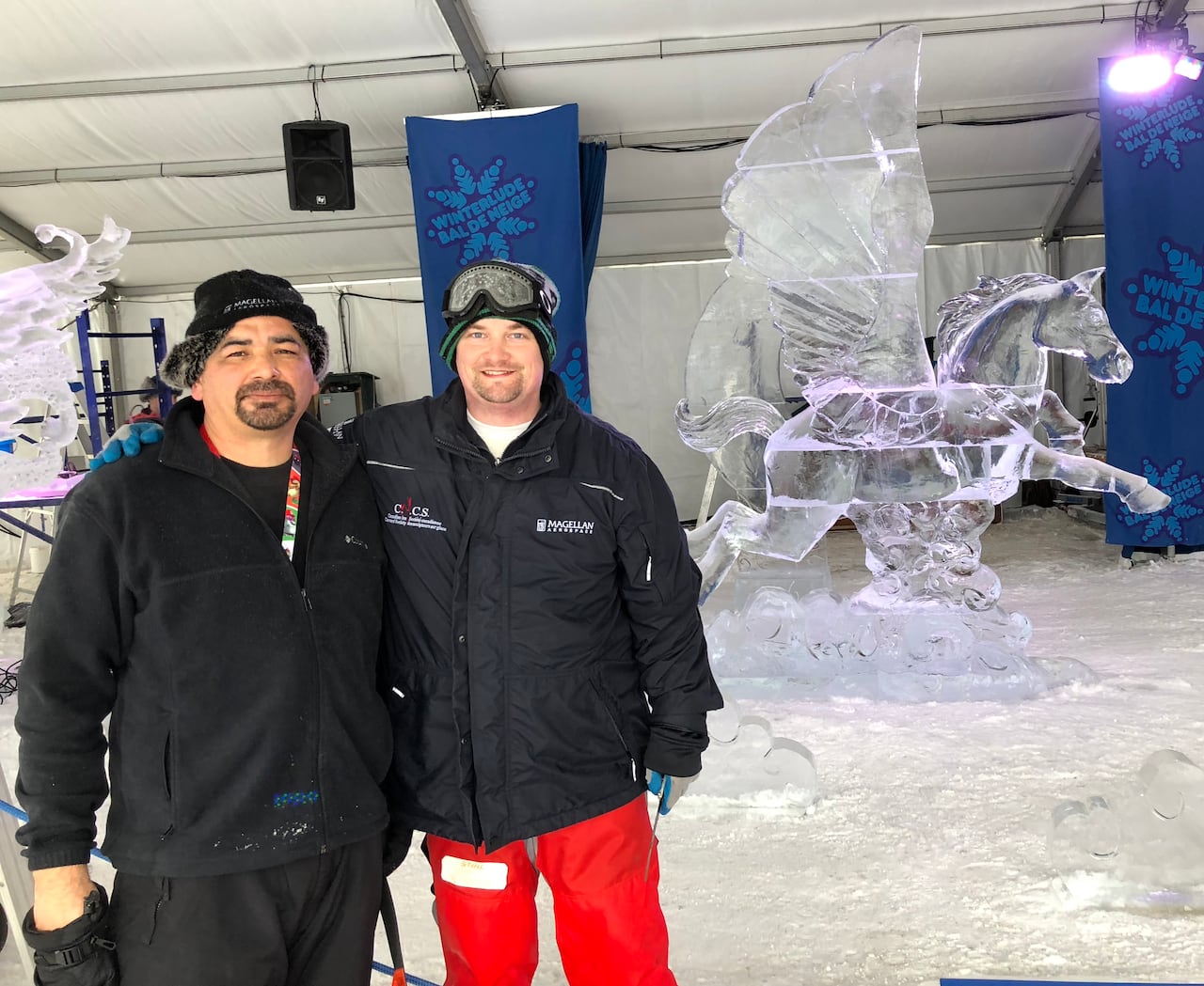 Two friends stand before their ice sculpture of Pegasus.