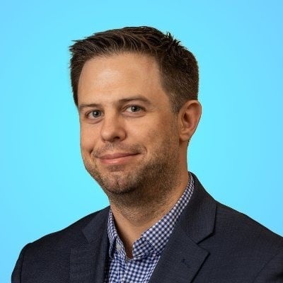 A man in a checked shirt and wearing a blazer.