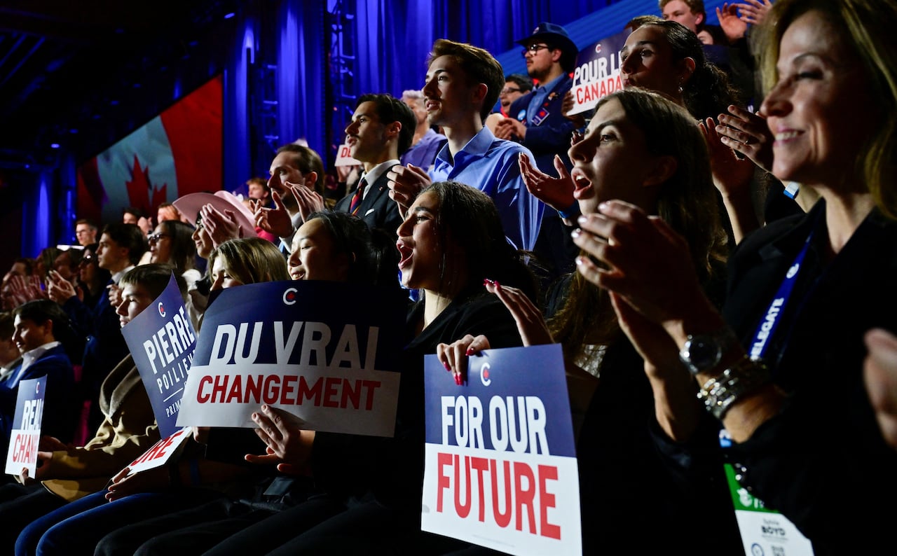 A crowd of people cheer and hold signs.