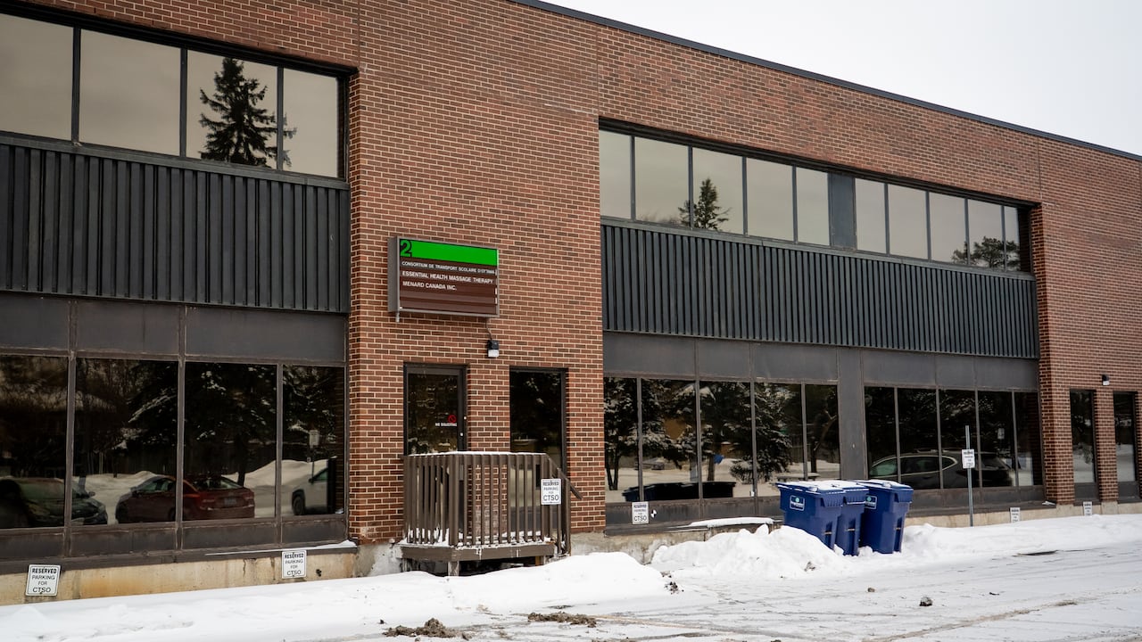 The snow-covered parking lot of a brick building.