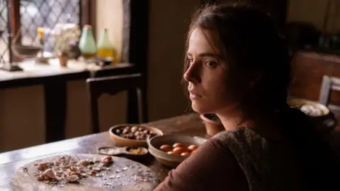 Agata Grzybowska/Focus Features Jessie Buckley as Agnes, sitting at a kitchen table