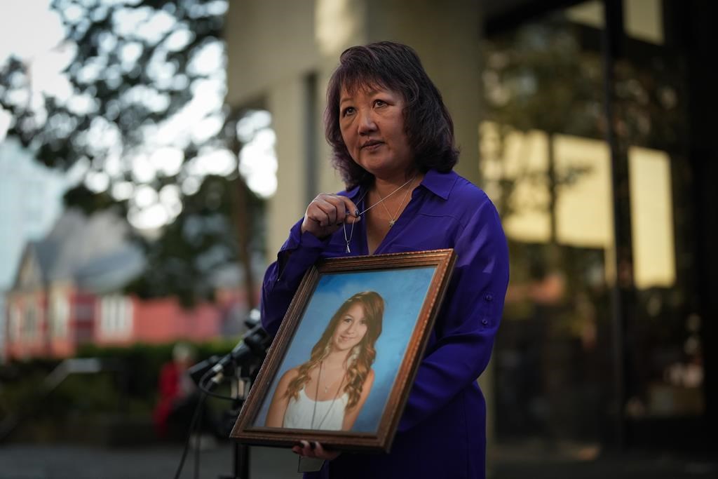 Carol Todd holds a photo of her late teenage daughter Amanda Todd, who died by suicide in 2012, and the necklace she was wearing in the school photo, outside B.C. Supreme Court