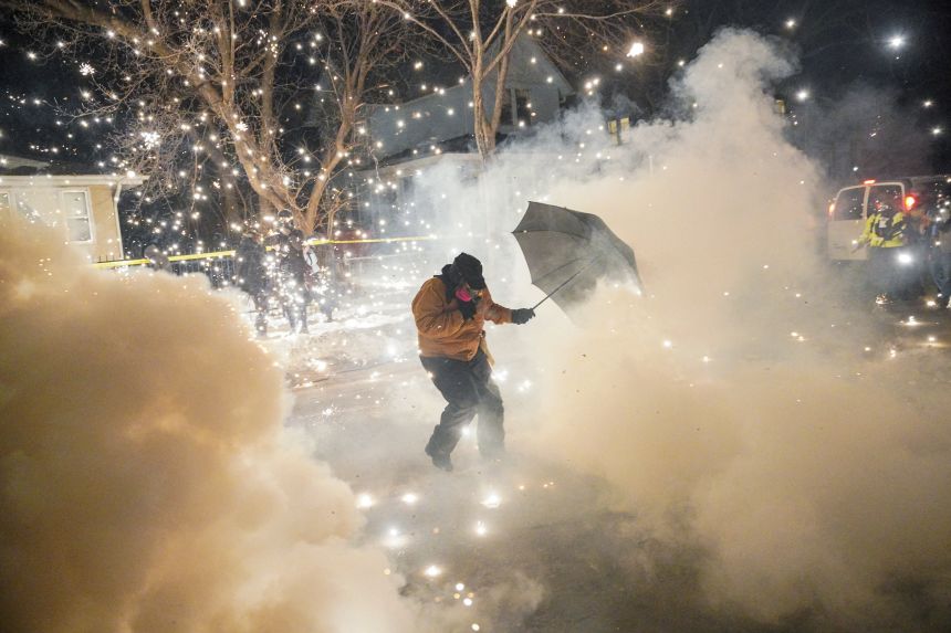 A protester shields themselves as federal agents fire tear gas and munitions in Minneapolis on Wednesday.