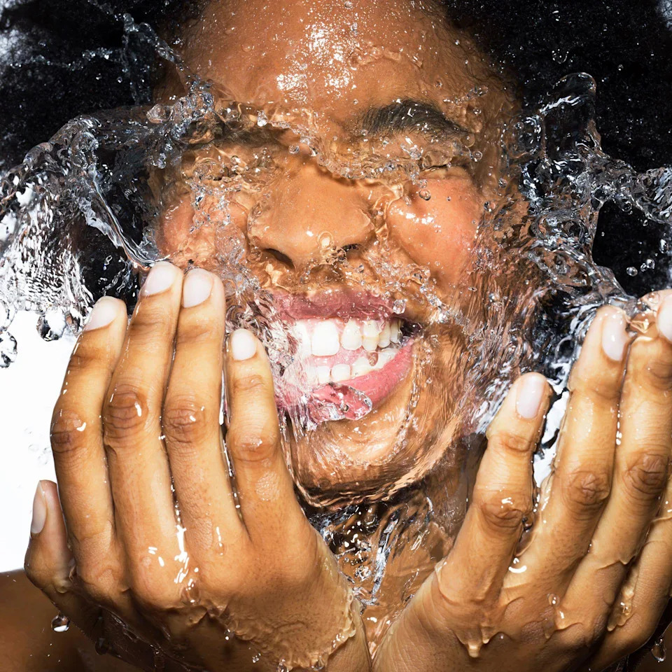 Young female splashing face with water 