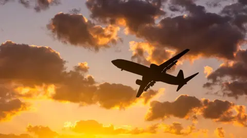 Getty Images Airplane at sunset above the clouds. Travel by air