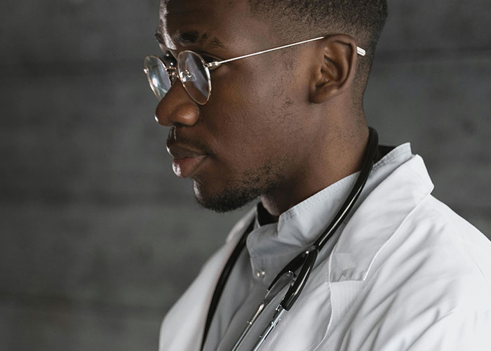 Young medical professional wearing glasses and a white coat with stethoscope, illustrating worst things said to patients.