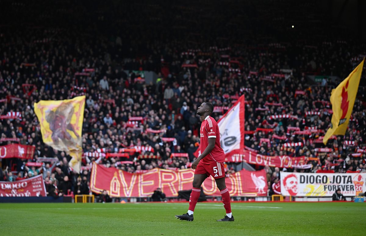 Ibrahima Konate walks in front of banners and flags on the Kop.
