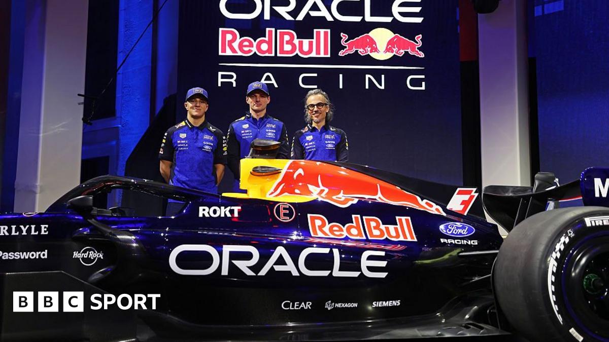 Isack Hadjar, Max Verstappen and team principal Laurent Mekies stand behind the new Red Bull car during the Red Bull Racing season launch at Michigan Central Station