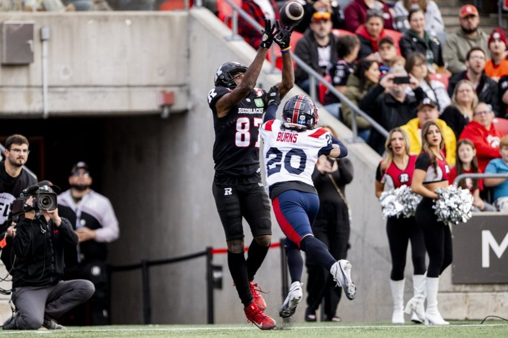 Ottawa Redblacks wide receiver Eugene Lewis (87) scores a touchdown as Montreal Alouettes defensive back Lorenzo Burns (20) attempts a block during first half CFL action in Ottawa, Saturday, Oct. 18, 2025. THE CANADIAN PRESS/Spencer Colby