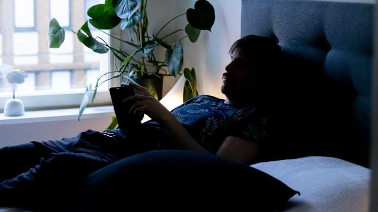 A man scrolls in bed 