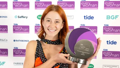 Everywoman Rose Skuse smiles, holding her entrepreneurship award