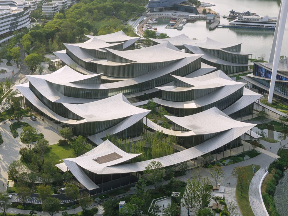 Modern architectural complex with curvilinear roofs surrounded by greenery.