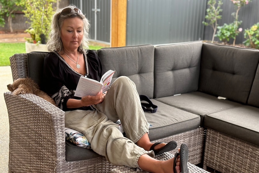 Karen Duncan sits on a chair reading a book.