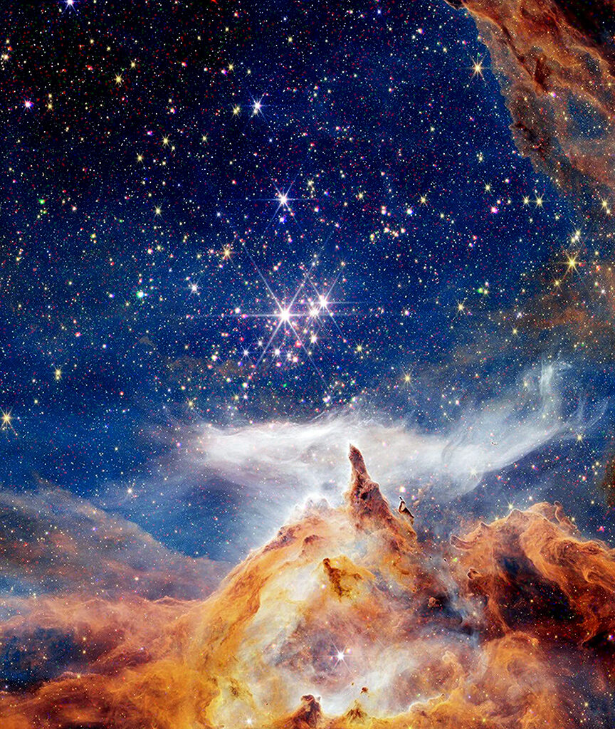 A winter scene fit for a holiday greeting card. Above what appears to be a fantastical snowy mountainscape, is a brilliant blue sky packed with colorful lights. The golden mountainscape is in fact part of the nebula NGC 6357, as captured by NASA's James Webb Space Telescope. The green, red, and golden lights in the blue sky above are bursts of high-energy X-rays from active stars, detected by Chandra.