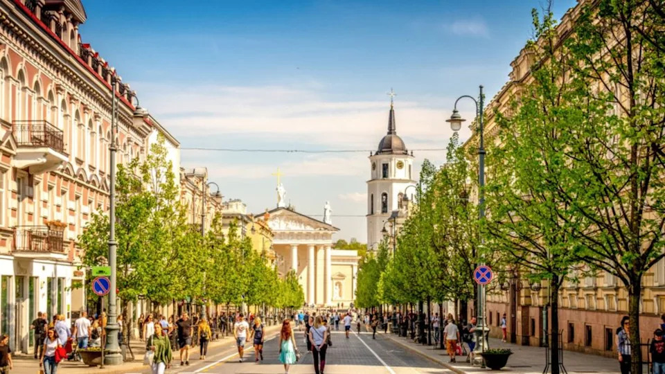 View to Vilnius city street -Gedimino avenue, Vilnius Cathedral and bell tower with people walking and riding bike in sunny day