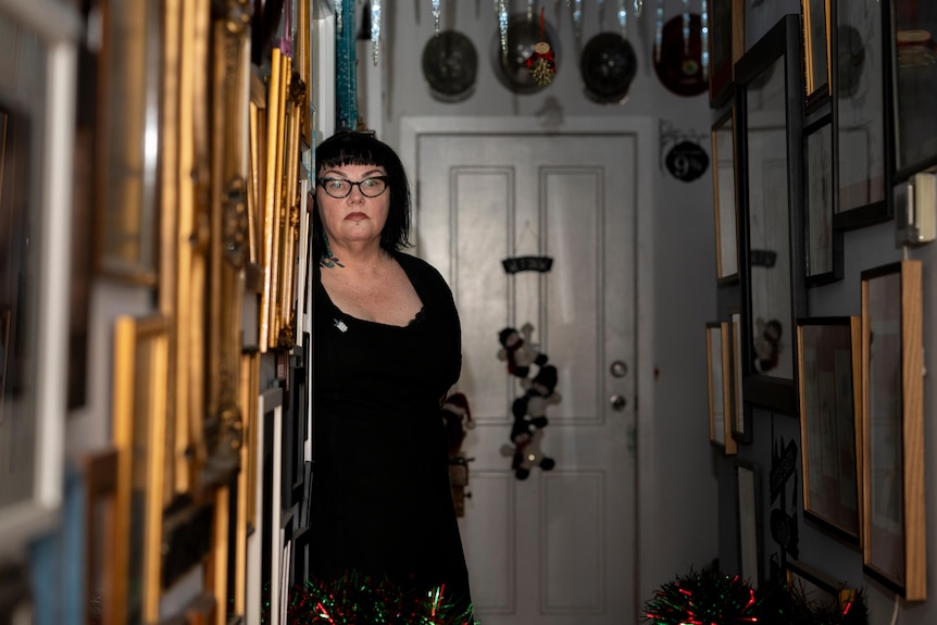 LJ stands in a hallway covered in gold frames.