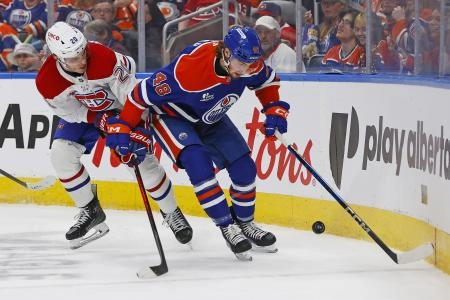 October 23, 2025; Edmonton, Alberta, Canada; Noah Philp (48), forward for the Edmonton Oilers, and Juraj Slafkovsky (20), forward for the Montreal Canadiens, battle for a loose puck along the boards during the second period at Rogers Place.