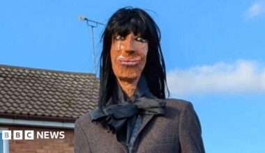 An effigy of Claudia Winkleman sitting on a garden fence.