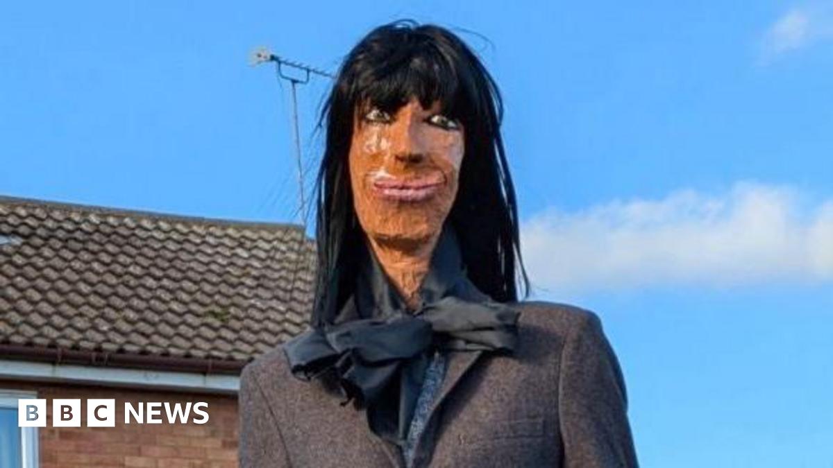 An effigy of Claudia Winkleman sitting on a garden fence.