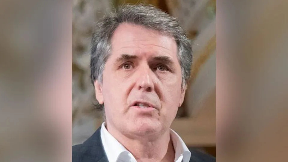 Steve Rotheram with grey hair wearing a grey suit and white shirt with the top button undone.