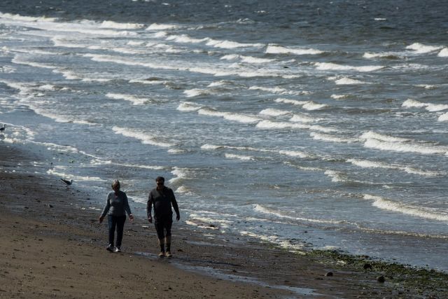 Strong winds whip up waves as a woman and man walk along the beach at English Bay in Vancouver, on Sunday May 5, 2019. THE CANADIAN PRESS/Darryl Dyck