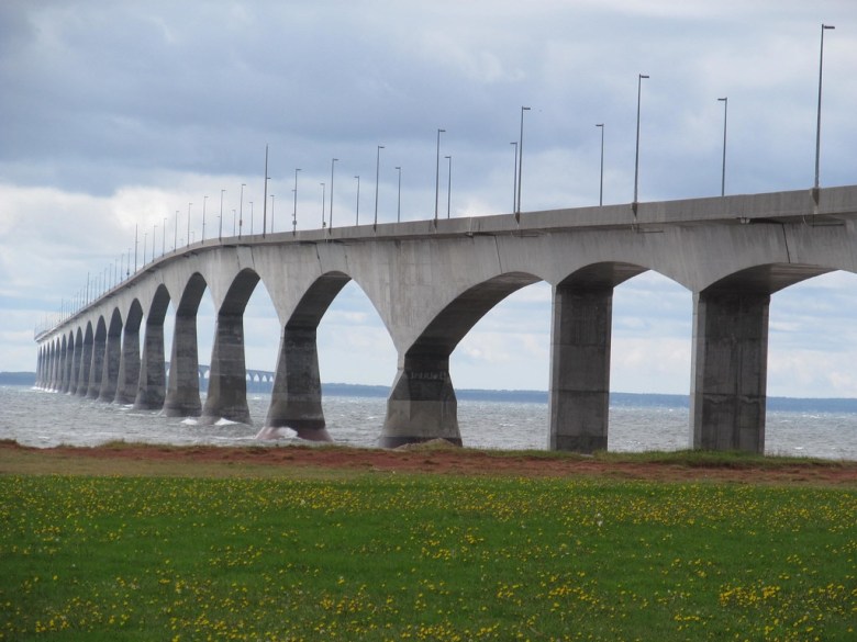 Concrete bridge with grass in the foreground and water in the background