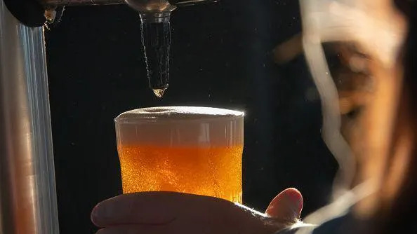 A golden pint of beer that has just been poured with a foaming head
