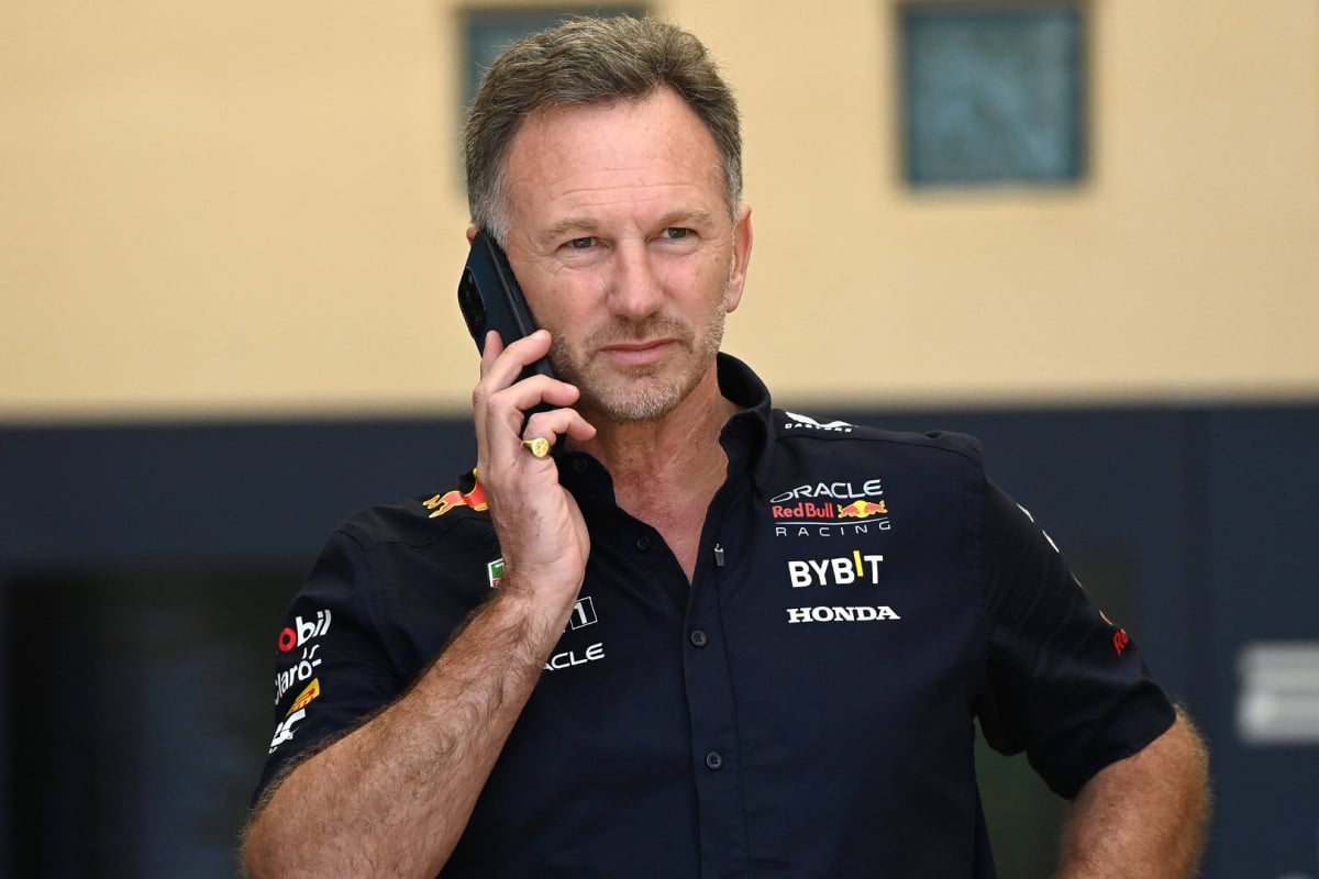 Horner in Red Bull kit looking down at his phone