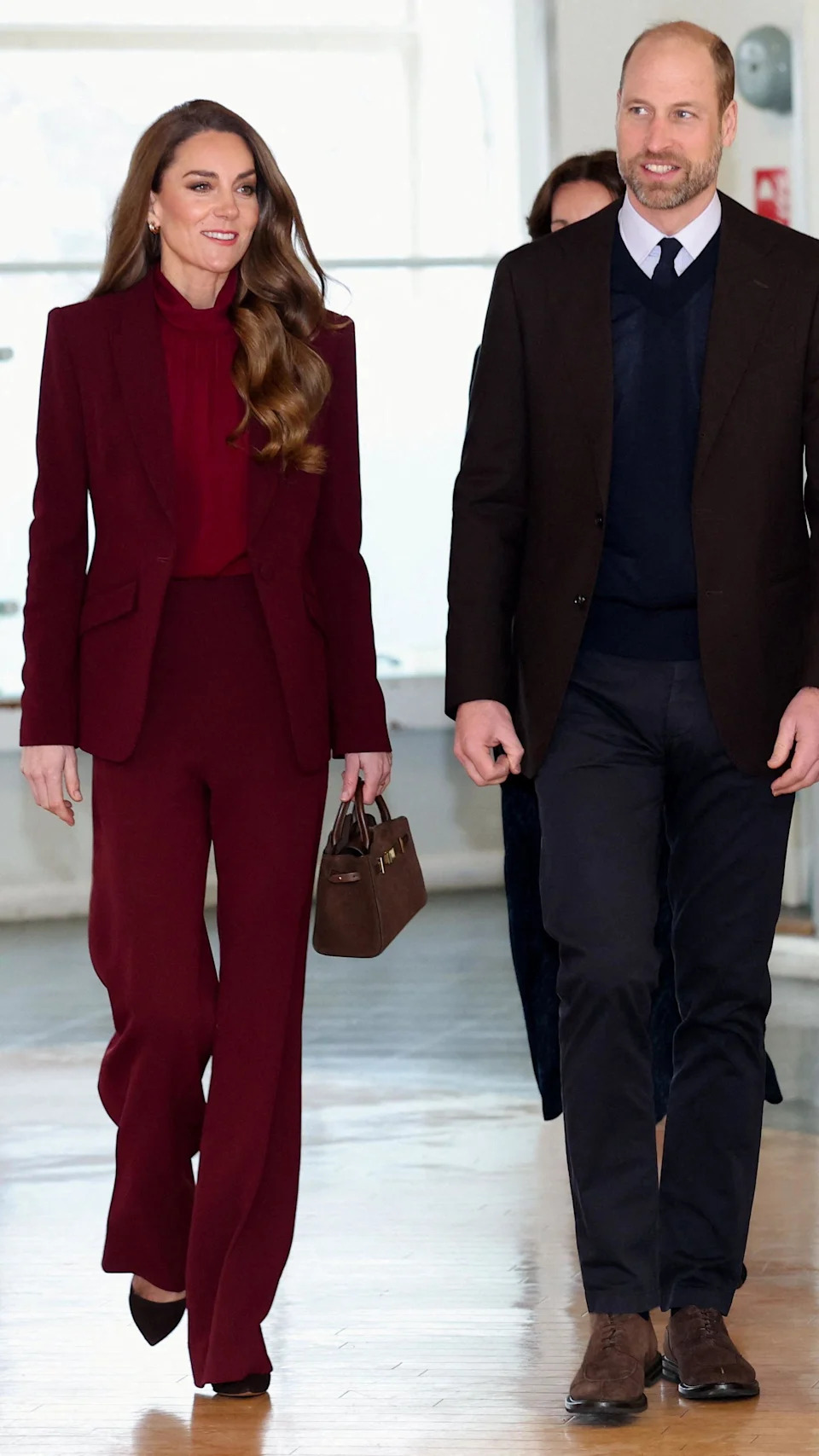 Catherine, who wore her hair down and carried a small handbag, was dressed in a burgundy trouser suit with matching blouse, while William wore a v neck jumper over his shirt and tie, with his suit jacket.
