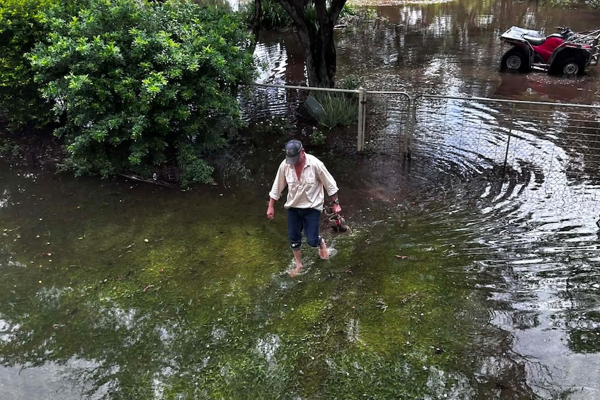 Man walking floodwater on property. 