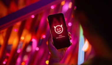 Female hand holding smartphone showing an evil with devil horn on her AI chatbot conversation app in the city. Illustrating the ideas around the risks and dangers of Artificial Intelligence (AI).