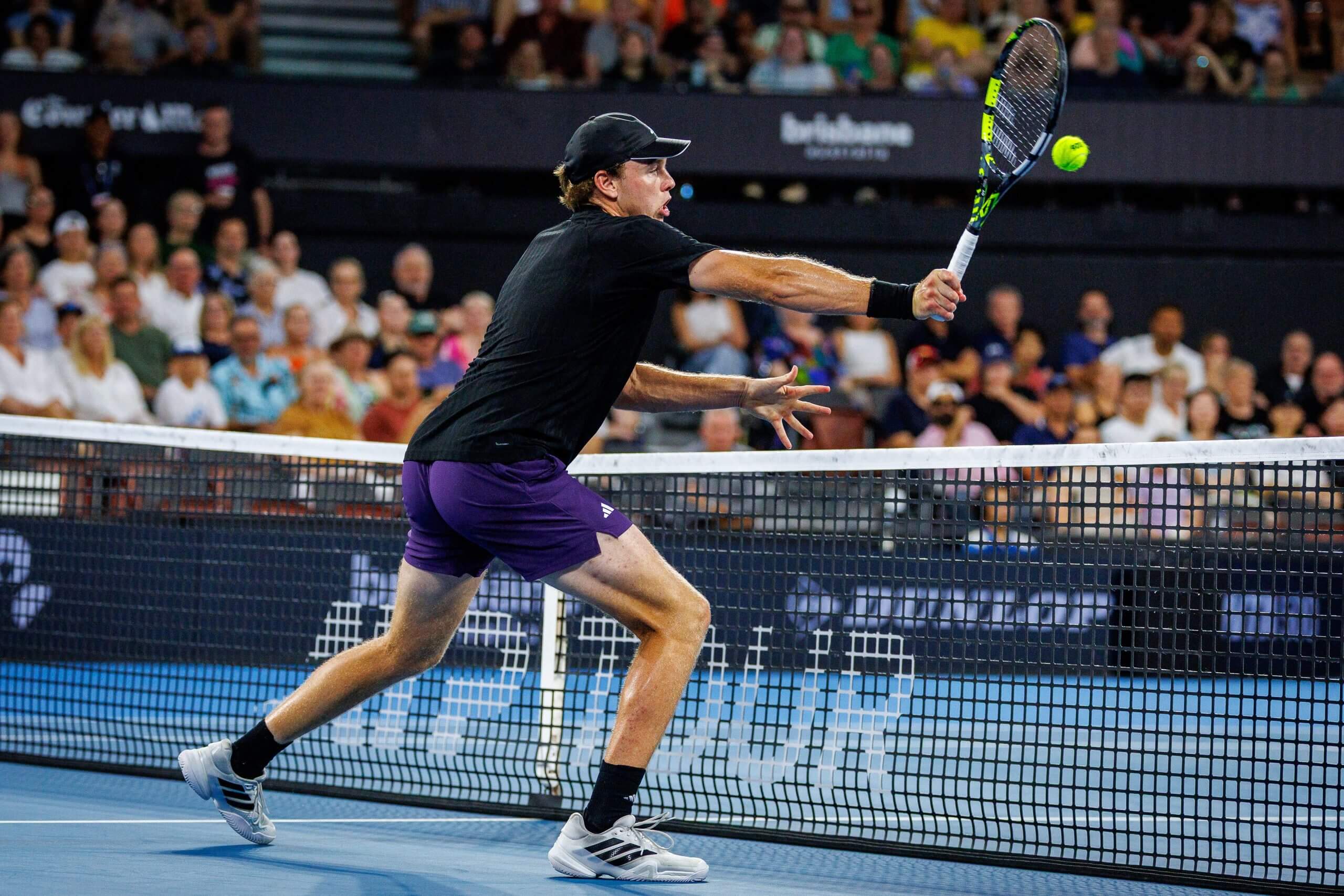 Alex Michelsen closes on a forehand volley right on top of the net, stretching to meet the ball.