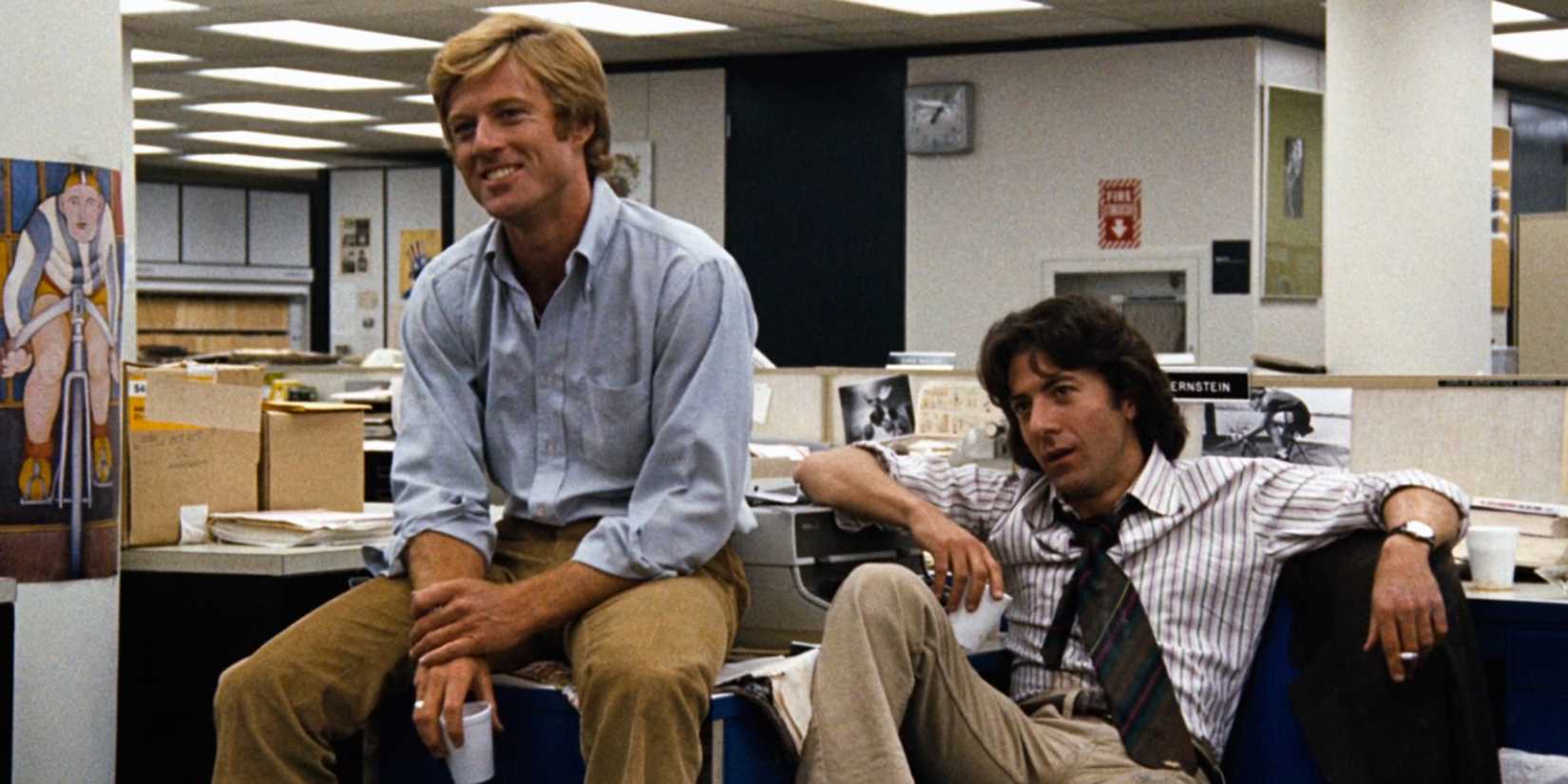 Robert Redford and Dustin Hoffman sitting at a desk in All the President's Men.