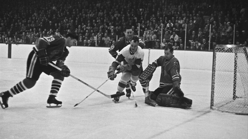 Detroit Red Wings' star Gordie Howe (9) charges in but is ganged up on the three Chicago players, Al MacNeil (19), Doug Jarrett (20), and goalie Glenn Hall, who defend against the shot in first period of their NHL game in Chicago, March 16, 1966.  (AP Photo/Paul Cannon)