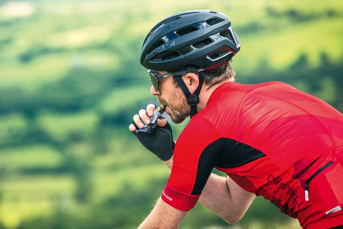 Road cyclist in red taking on nutrition