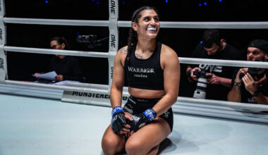 Natalie Salcedo kneels and smiles in the ring