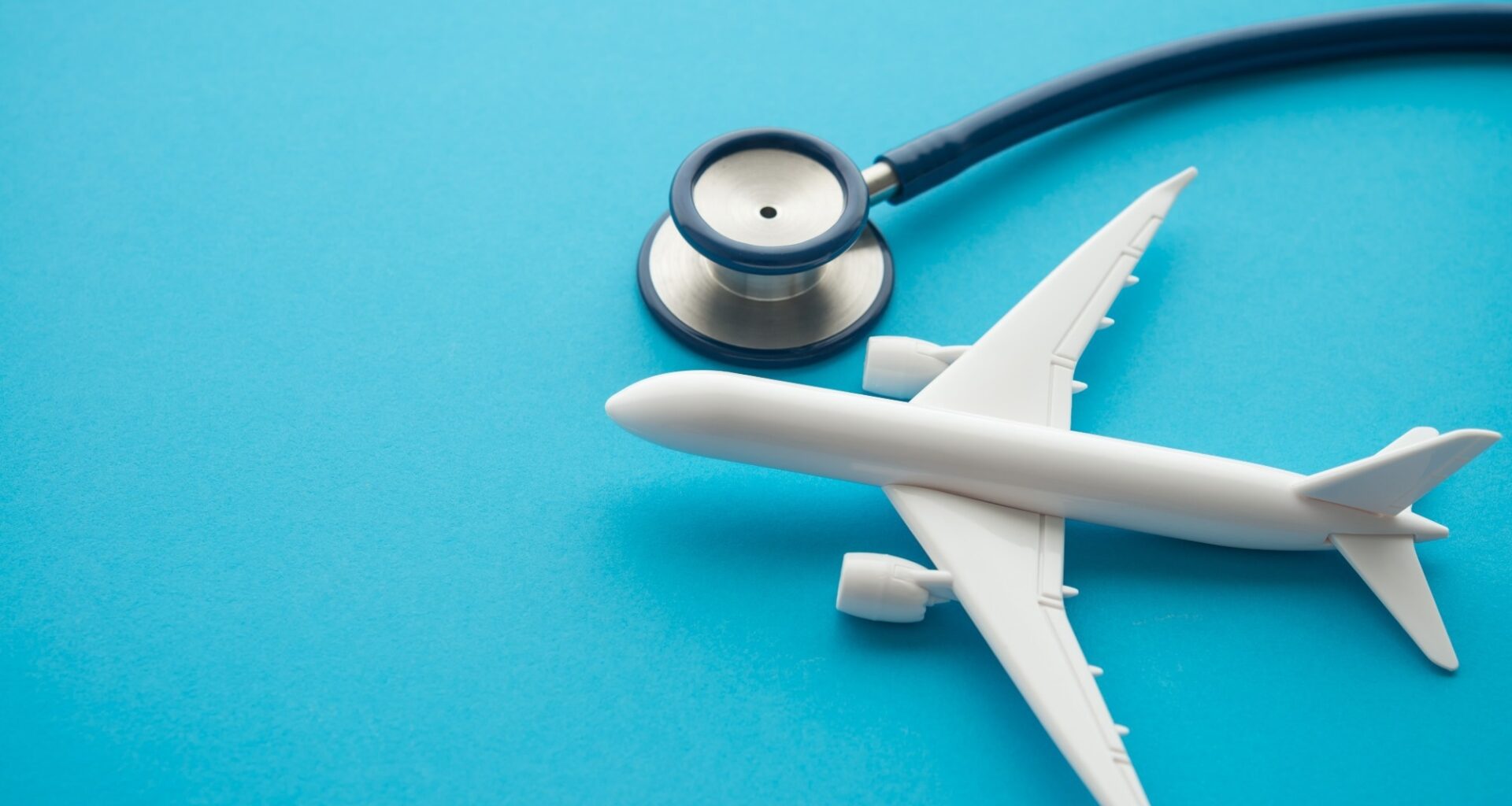 Airplane and stethoscope on blue background with copy space. Going abroad for medical care. Medical tourism is when a person travels to another country for medical care.