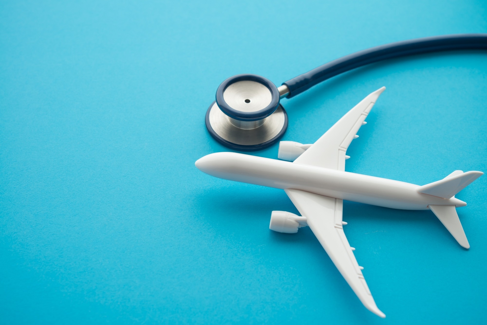 Airplane and stethoscope on blue background with copy space. Going abroad for medical care. Medical tourism is when a person travels to another country for medical care.