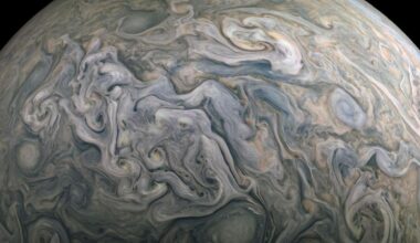 A close up of Jupiter's surface in space where clouds of blue and gray swirl.