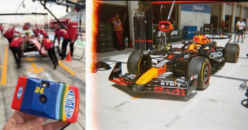 A person holds a colorful disposable camera in the foreground, while in the background there are blurred Formula 1 pit crew members; on the right, a Red Bull F1 car is parked in the pit lane.