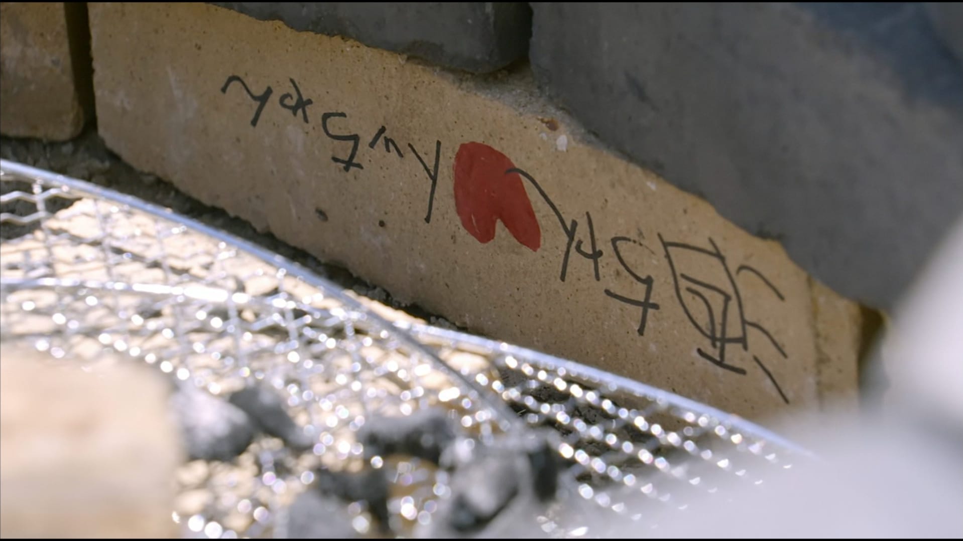 Names written on a brick inside of a fire pit. 