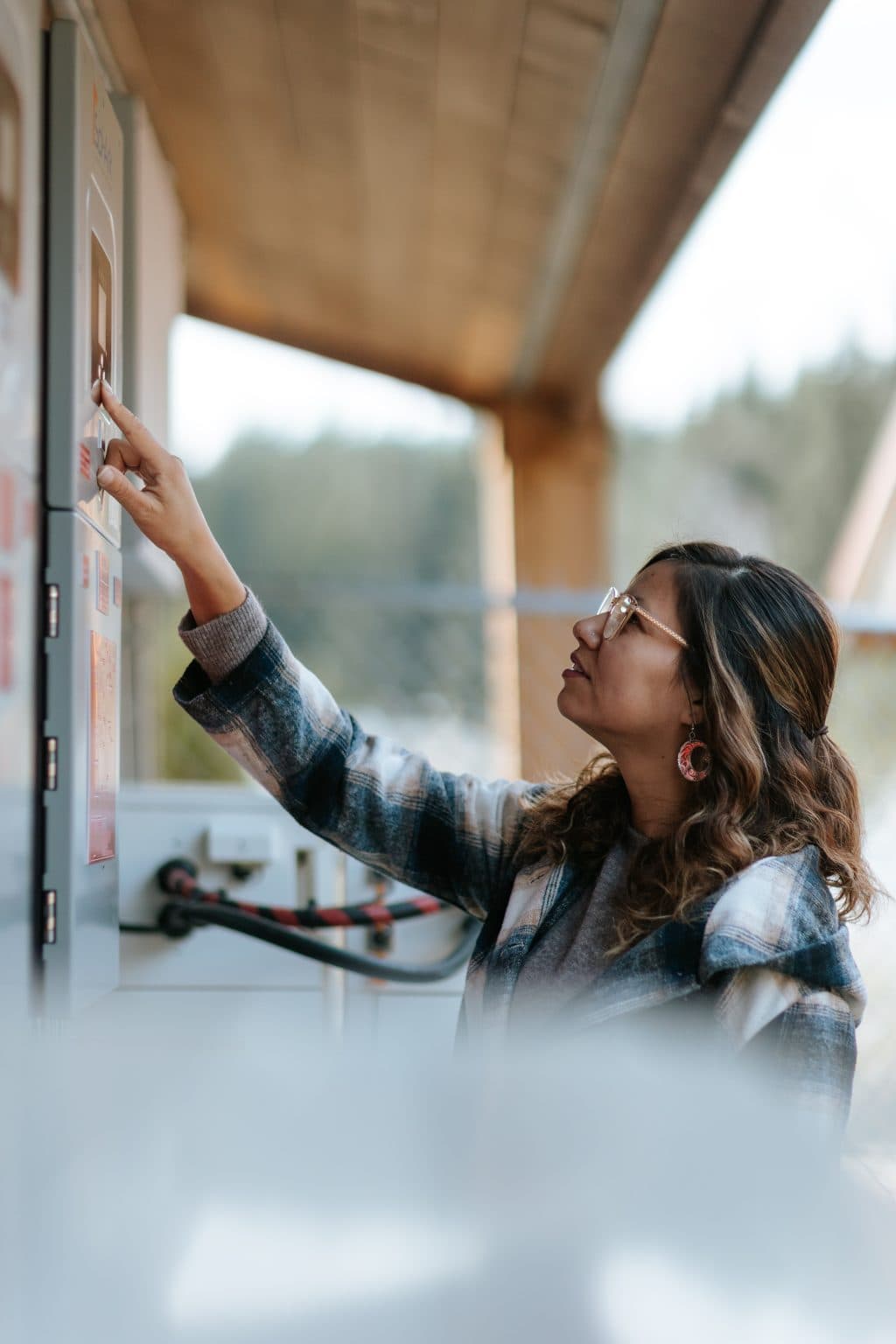 Kara Wilson holds her hand up to the wall, her finger tracing down writing on a grey panel, which is part of the solar equipment at Quatsino's daycare.