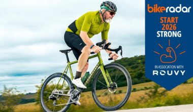 Warren wearing green on road bike with Rouvy banner