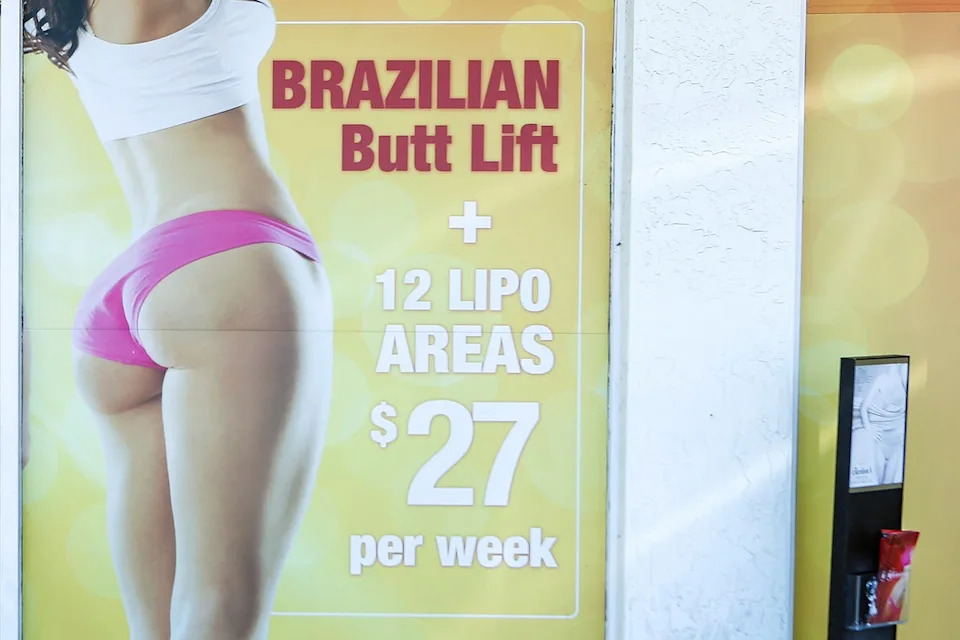 A window display advertises low-cost ‘Brazilian butt lift’ cosmetic surgery procedures outside a clinic in Miami (AP)