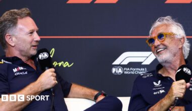 Christian Horner and Flavio Briatore speaking into FIA-branded microphones at a Formula 1 news conference