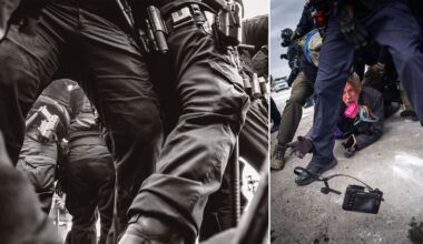 A man wearing a gas mask crouches on the ground amid armed police officers in tactical gear; a camera lies on the pavement nearby. The scene appears tense and chaotic.
