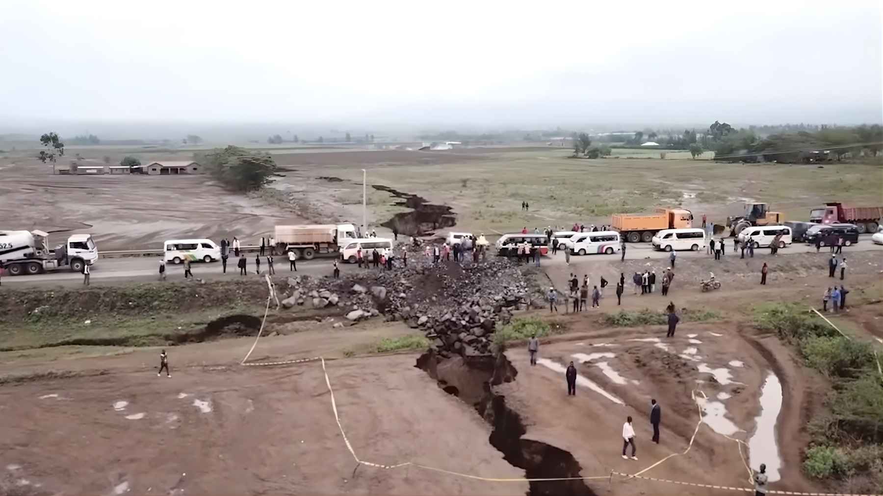 “People and vehicles gather beside a deep ground fissure that ripped across a road in Kenya, part of the East African Rift zone.”
