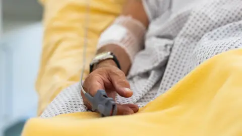 Getty Images A close up on a elderly patients hand. The person is in a hospital bed.